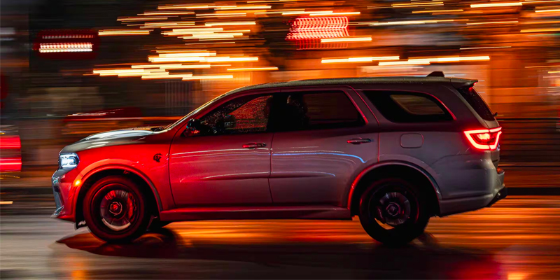 A silver Dodge Durango in motion with blurred lights at night.