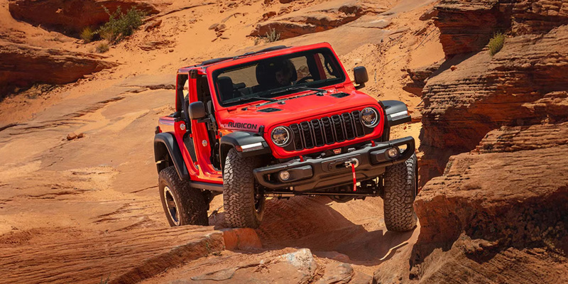 Red Jeep Rubicon rock crawling in the desert.