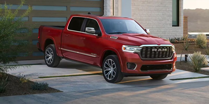 Red RAM pickup truck parked in a driveway outside a modern home.