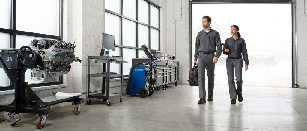 Two technicians walking through a modern auto repair workshop.
